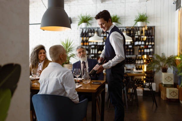 server pouring wine for guests at a restaurant table